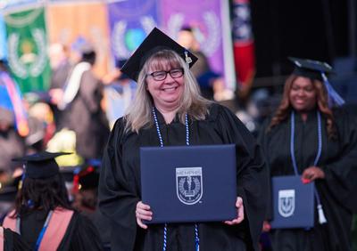 graduates hold diplomas at commencement