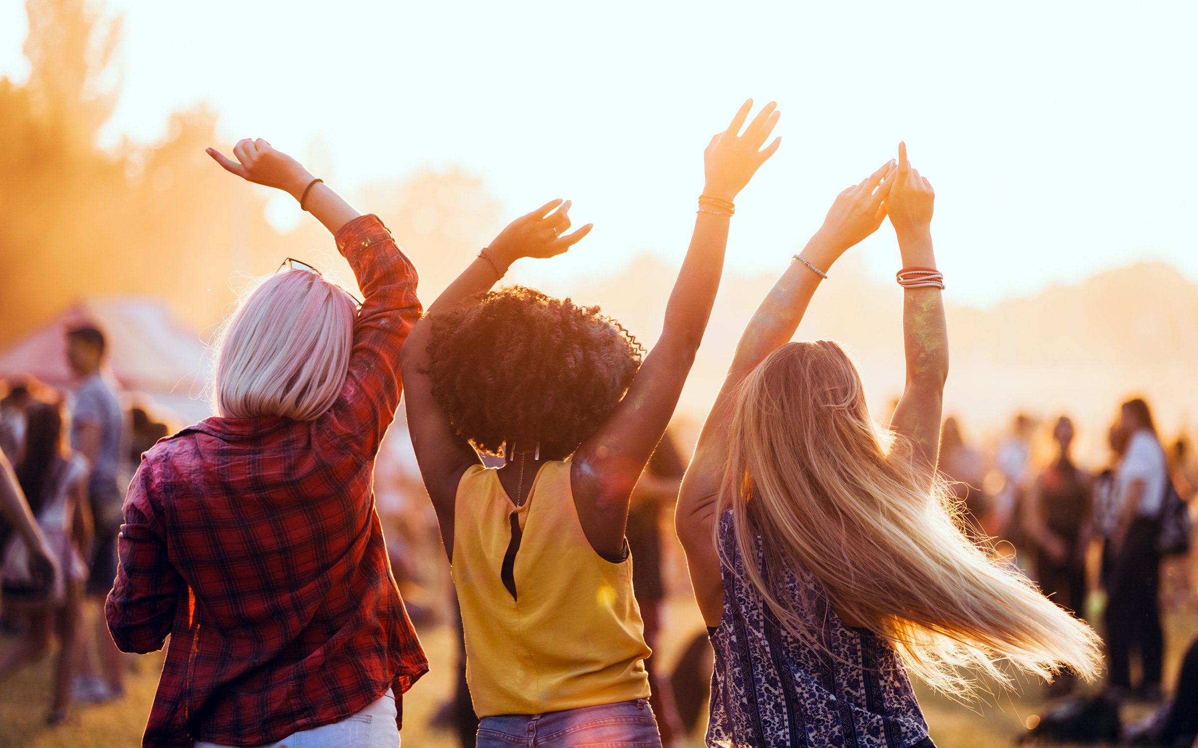 crowd of people dancing in sunshine at a festival