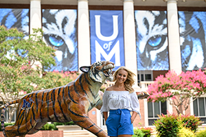 female student standing by tiger statue in front of Admin Building