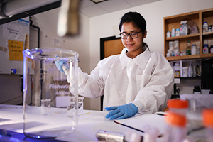 student conducts research in lab wearing protective gear