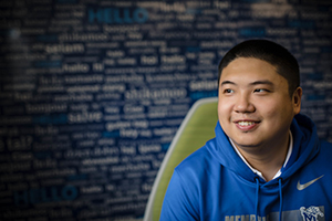 student in front of blue word wall