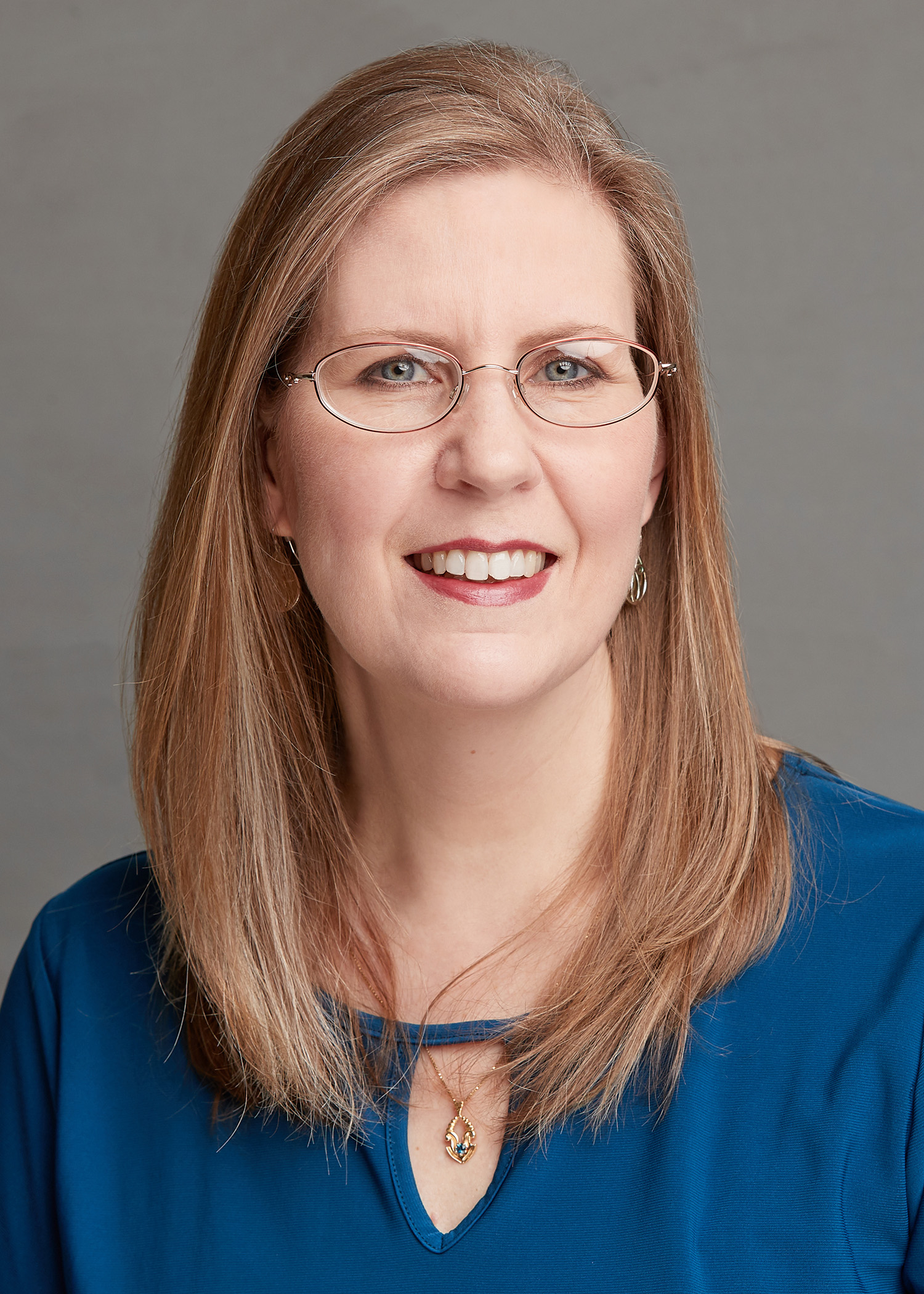 Rhonda Smothers is a light-skinned woman with strawberry-blonde hair and blue eyes.  Sh is wearing a blue shirt and glasses. 