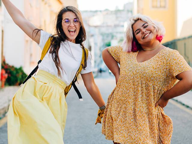 two female students smiling and waving