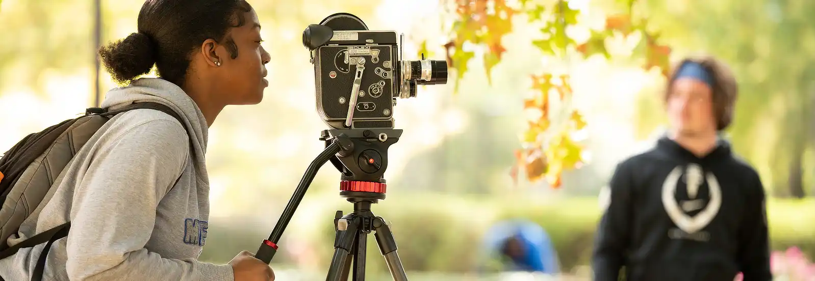 A communication student filming a class project alongside two instructors.