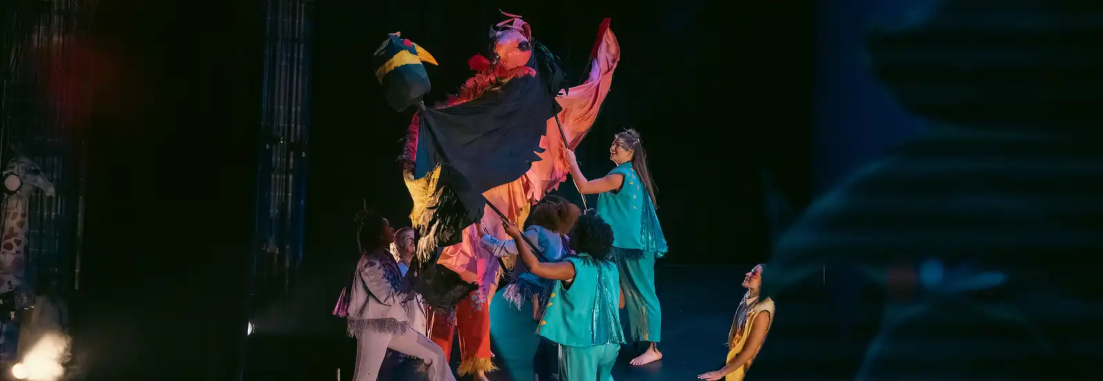UofM Theatre & Dance group performance on dim-lit emerald green background lighting on stage.