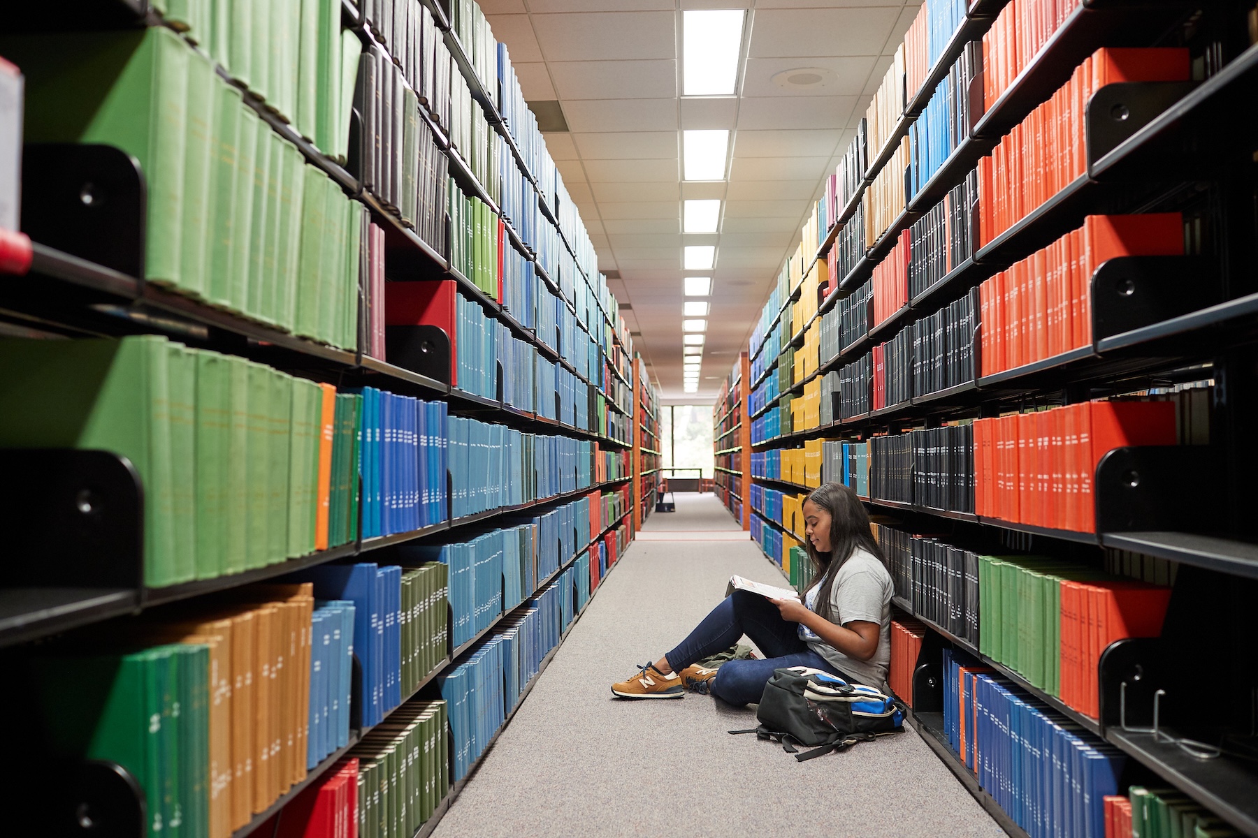 Student sits in a library writing on papers