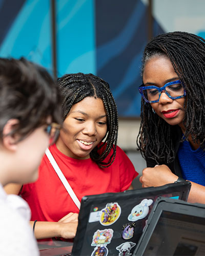 Students work with a faculty member during a technology-based learning activity.
