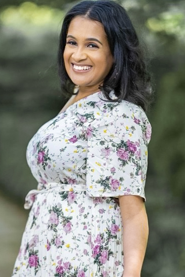 Photo of CPL Student Kaylan Mumford wearing a floral dress in front of a wooded backdrop.