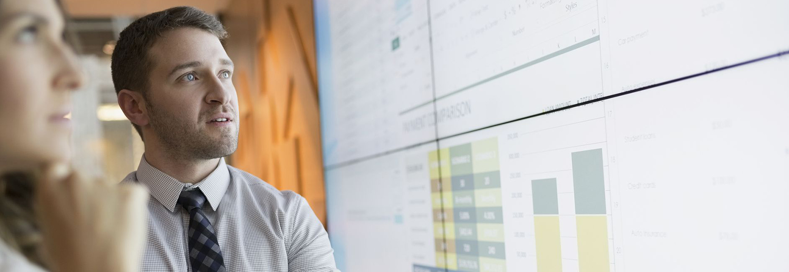 man and woman looking at data on large screen