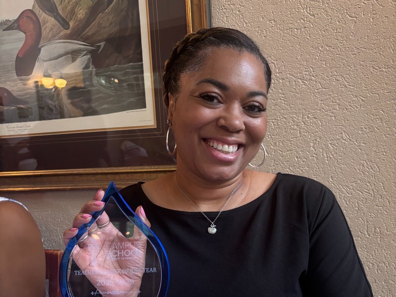 Darcy Dawn Robinson smiles while holding her 2025–26 Teacher Leader of the Year award.