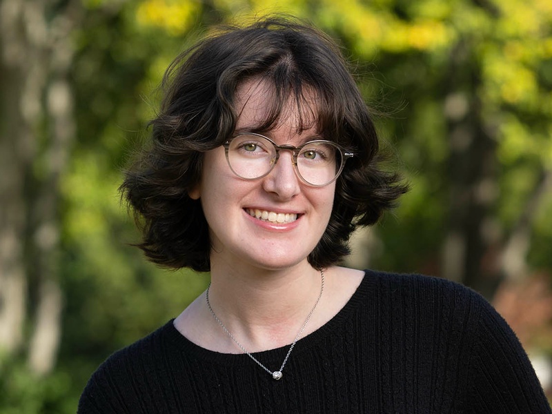 Isabel Parobek smiling outdoors in front of trees.