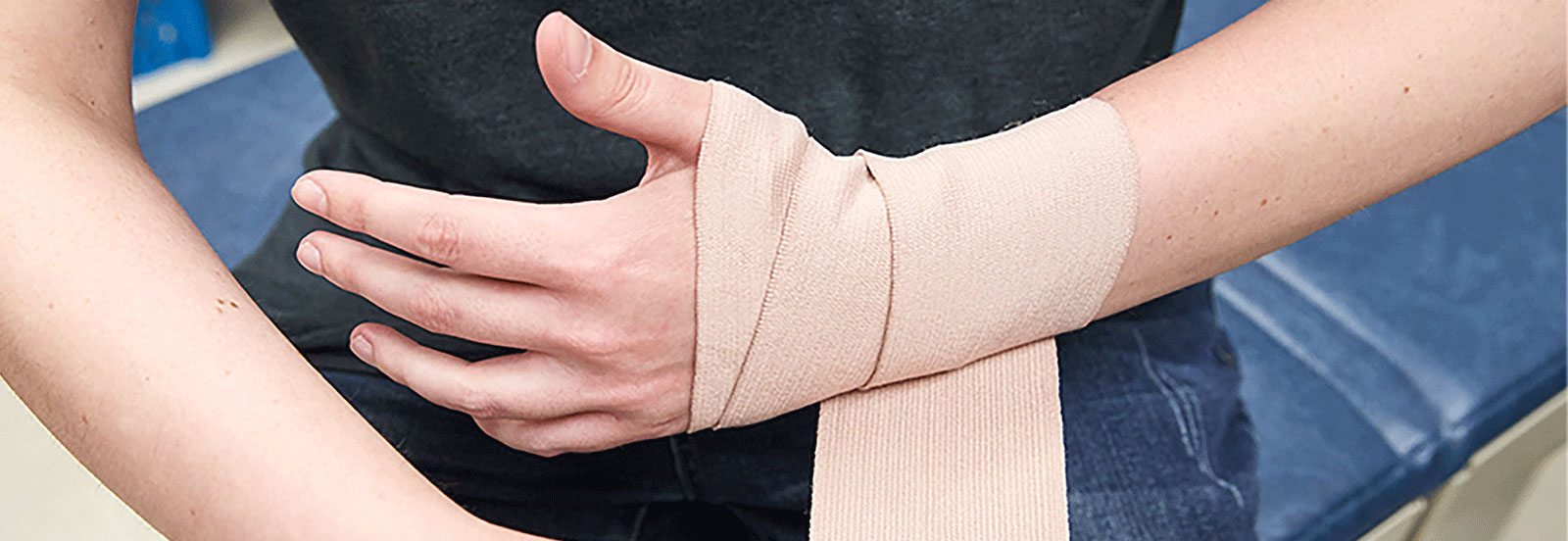 person wrapping bandage around sprained wrist
