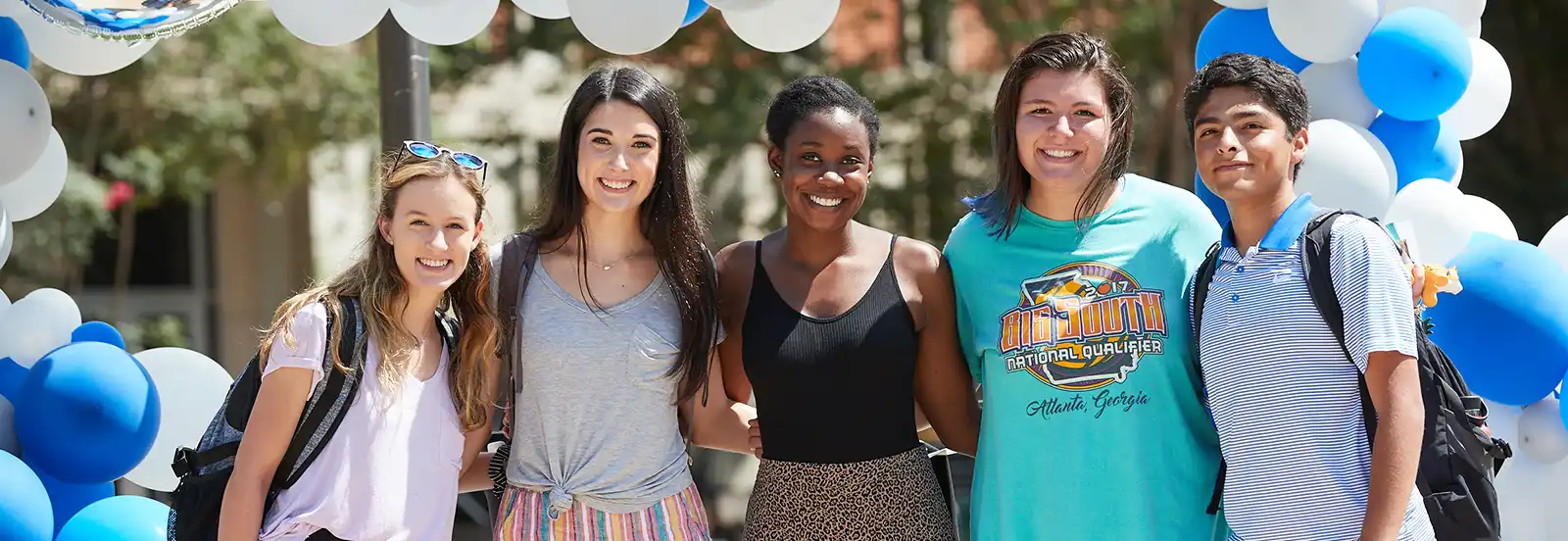 five students under a balloon arch 