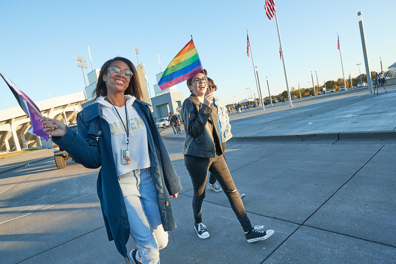 students holding LGBTQ+ pride flags at homehoming