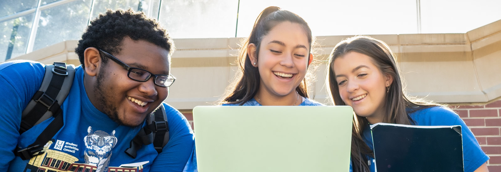 Three students using a laptop