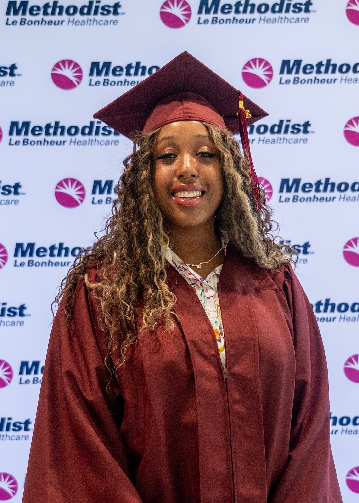 photo of African-American woman smiling wearing a maroon graduation gown and mortarboard.