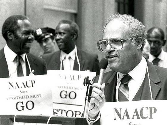 Ben Hooks wears an NAACP sign at apartheid protest.