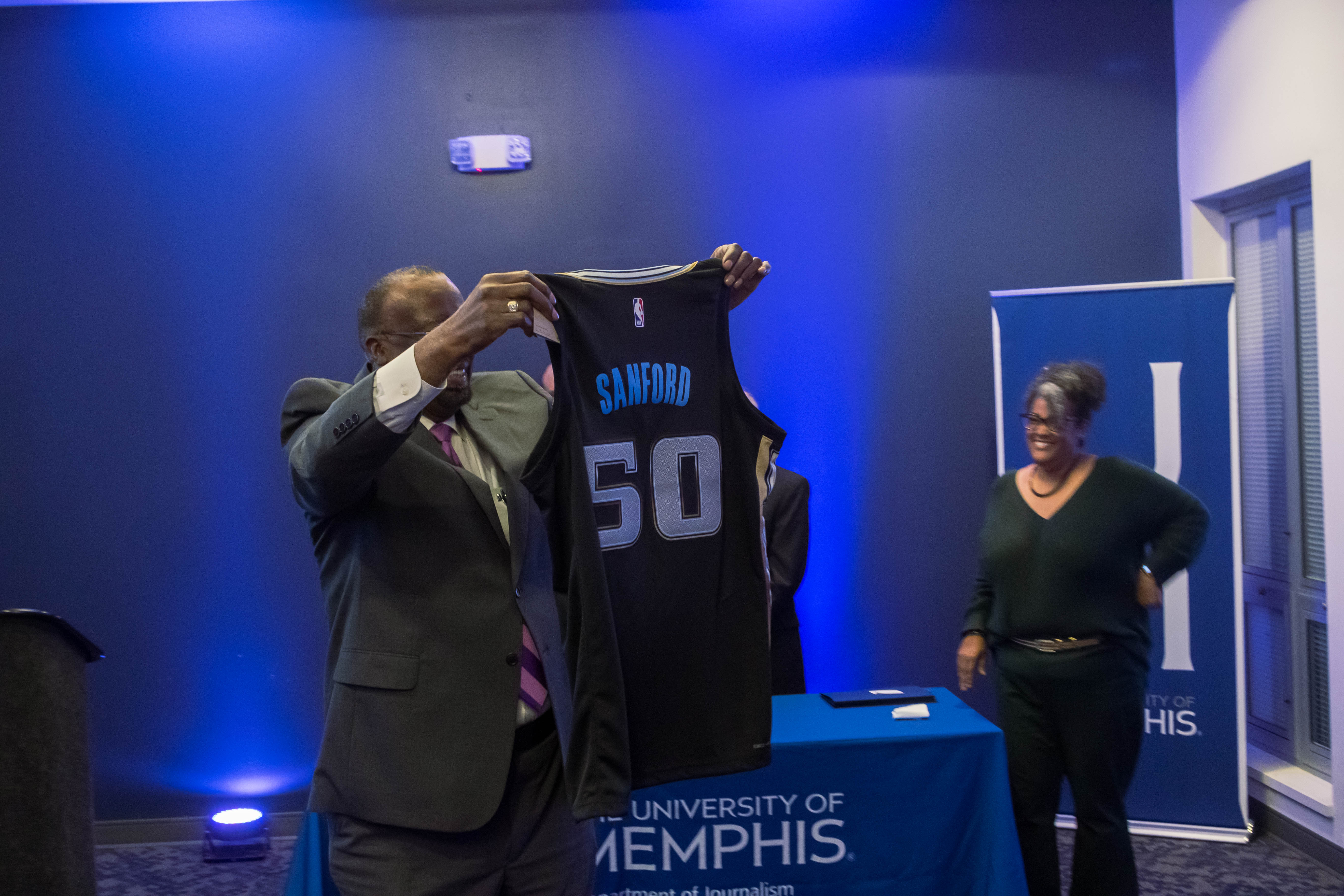 Professor Otis Sanford shows off one of the gifts he received  on the event of his retirement from the department.