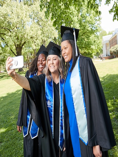 students taking a selfie in their graduation regalia