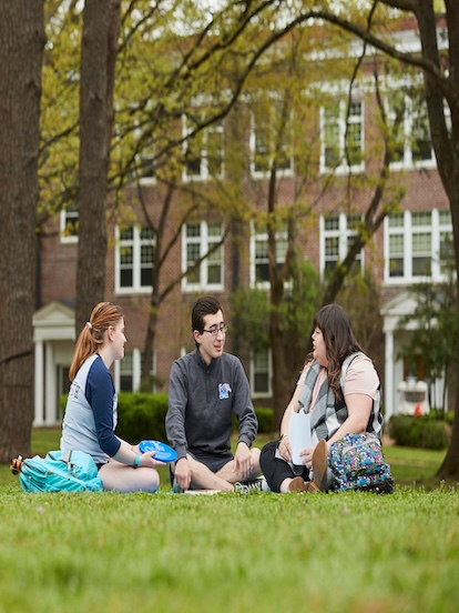 students sitting in grass enjoying conversation on campus