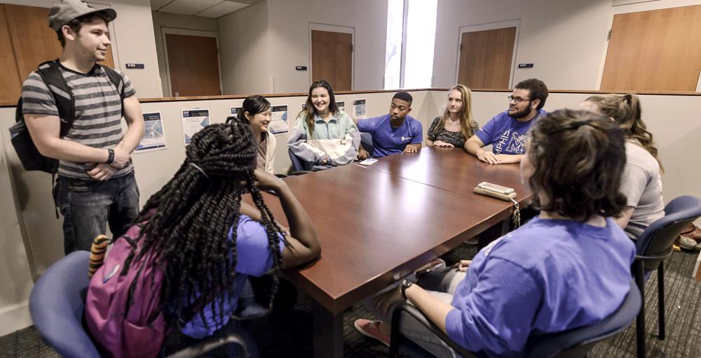 Student group meeting and chatting around meeting table within the Living Learning Complex (LLC) Lounge Area.