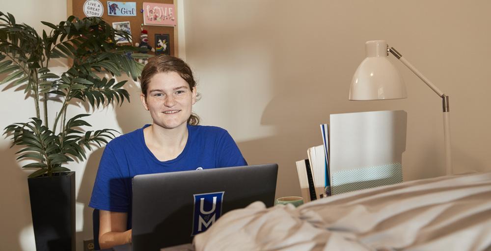 student with computer desktop in dorm room