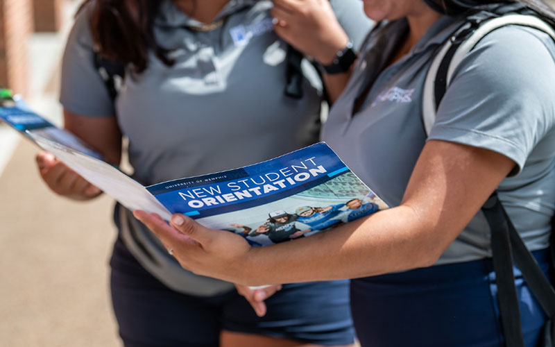 Two female guides reviewing the orientation folder