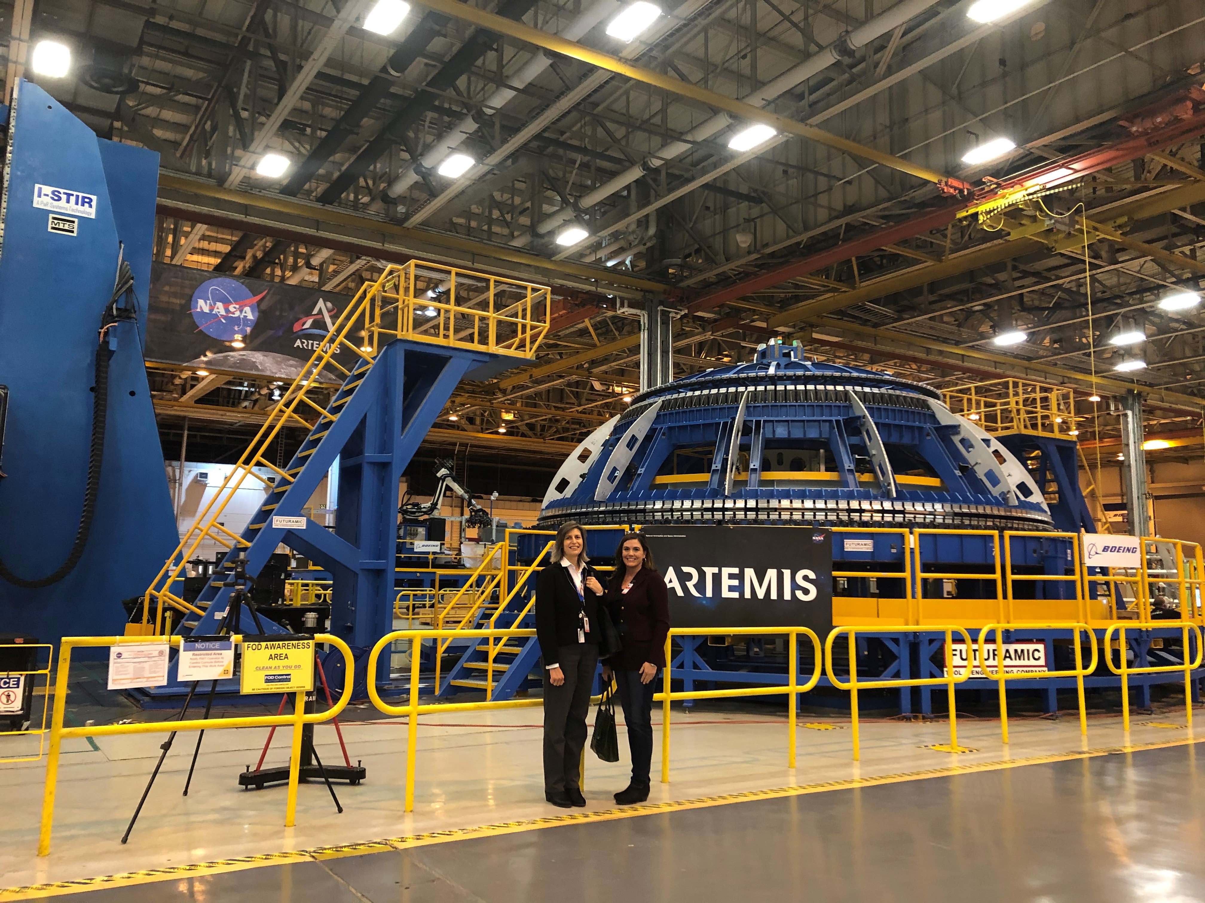 Michele Wilson and a fellow Davidson employee in front of a friction-stir welding fixture used to construct the dome ends on the LOX and Fuel tanks inside the Artemis rocket core stage at NASA’s Michoud Assembly Facility in New Orleans.
