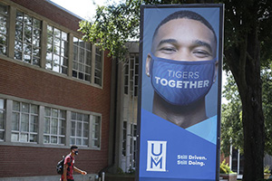 Student walking in Campus and a poster of Tiger Together 