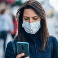 image of woman wearing face mask and looking at cell phone