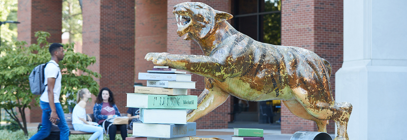 statue of tiger with paw on stack of books