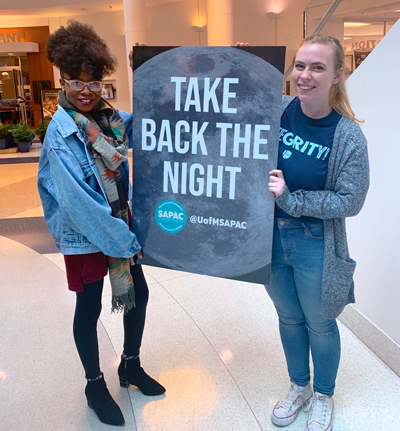 two students holding "take back the night" poster
