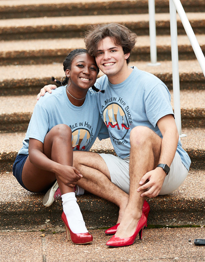 male and female student wearing red heels at "Walk a Mile in Her Shoes" event