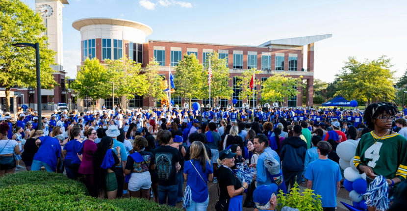 exterior view of the UC from the student plaza with hundreds of people dressed in school colors for an event