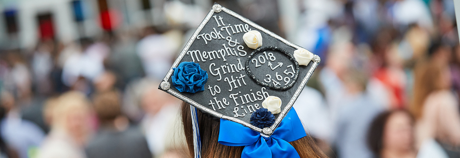 Student at commencement with mortar board that reads: It took time and Memphis grind to get to the Finish Line