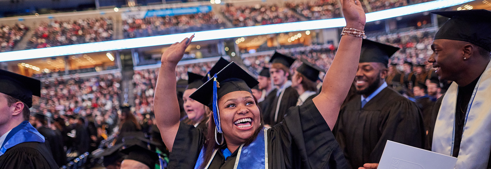 Graduate celebrating with arms raised in the air at Commencement ceremony