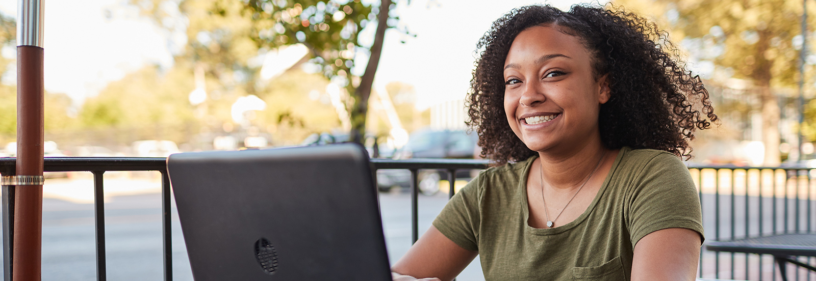 online student on laptop on patio at coffee shop