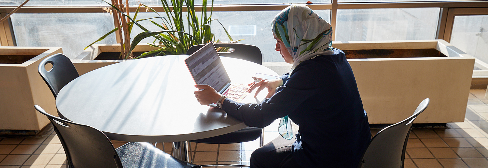 student sitting at table working on laptop in lobby