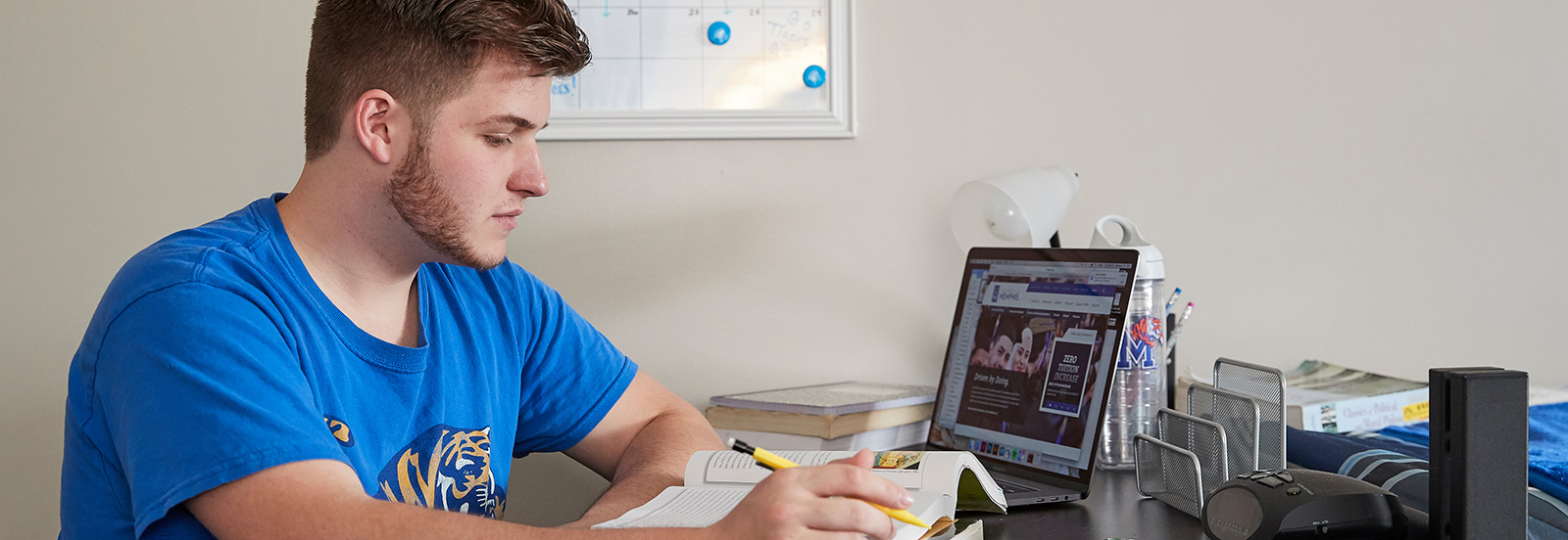 UofM student in dorm working on laptop