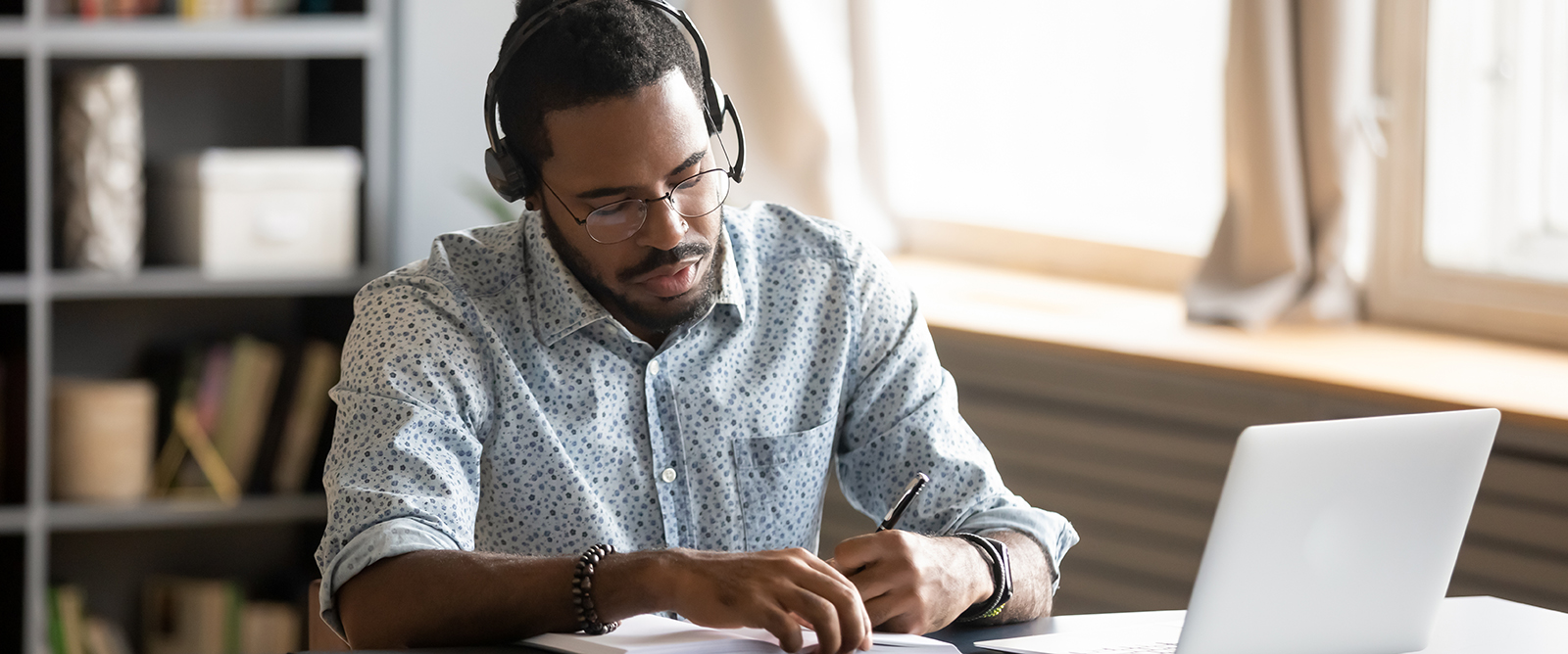 male student wearing headphones while looking at laptop