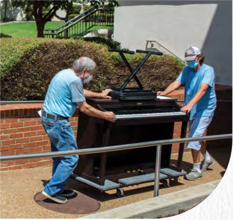 photo of two men loading piano into truck