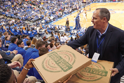 Dr. Rudd distributes pizzas to student section at basketball game