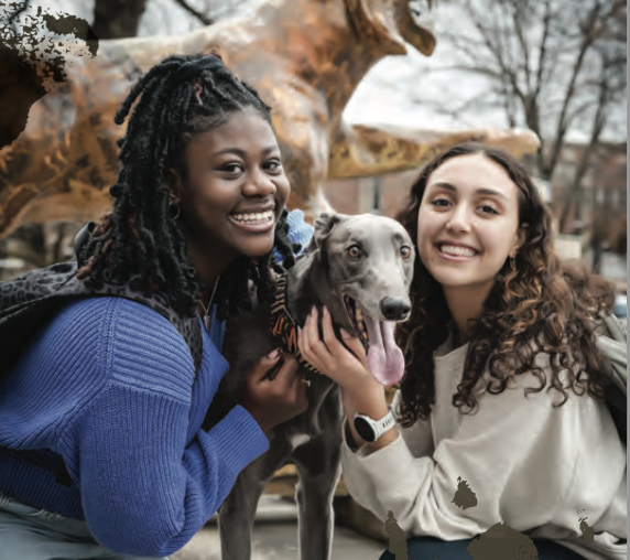 two students smiling with therapy dog