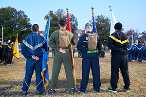 ROTC members representing different branches holding flags; photo from behind them