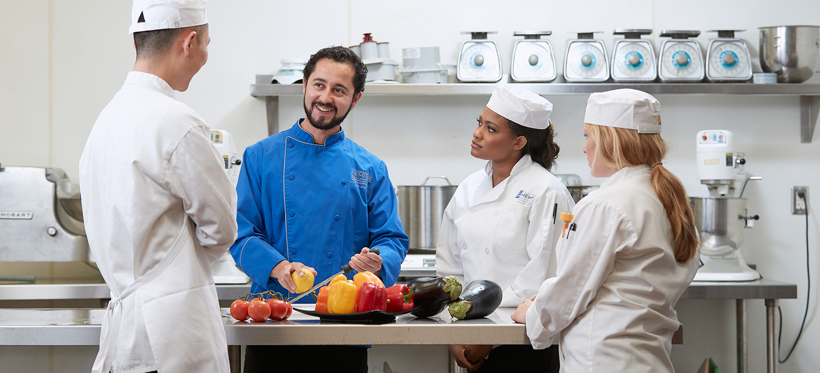 Chef teacher with students, showing how to cut vegetables