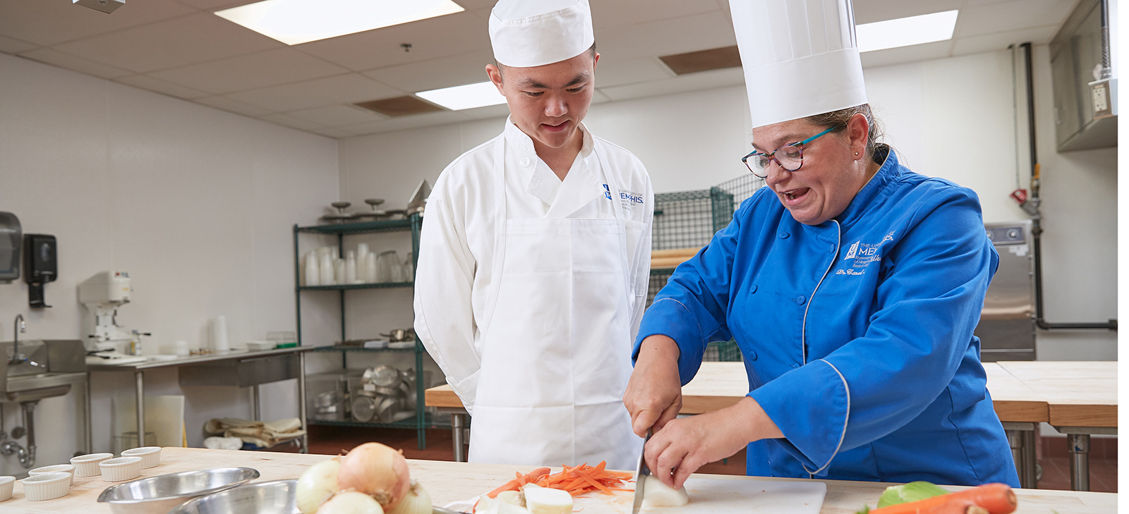 student teaching student to chop vegetables